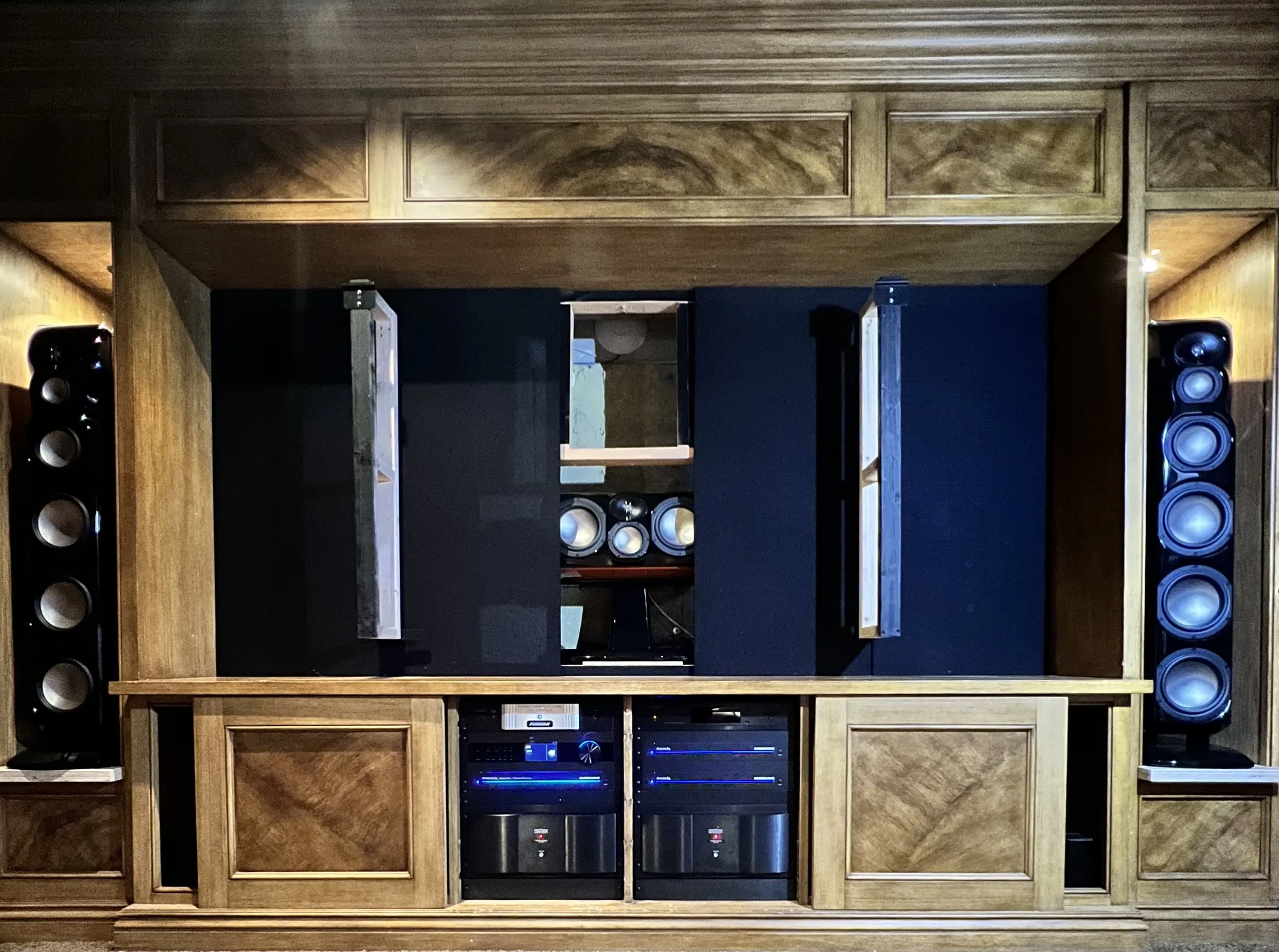 Custom wood media cabinet with tower speakers, subwoofers, and amplifiers integrated into the millwork