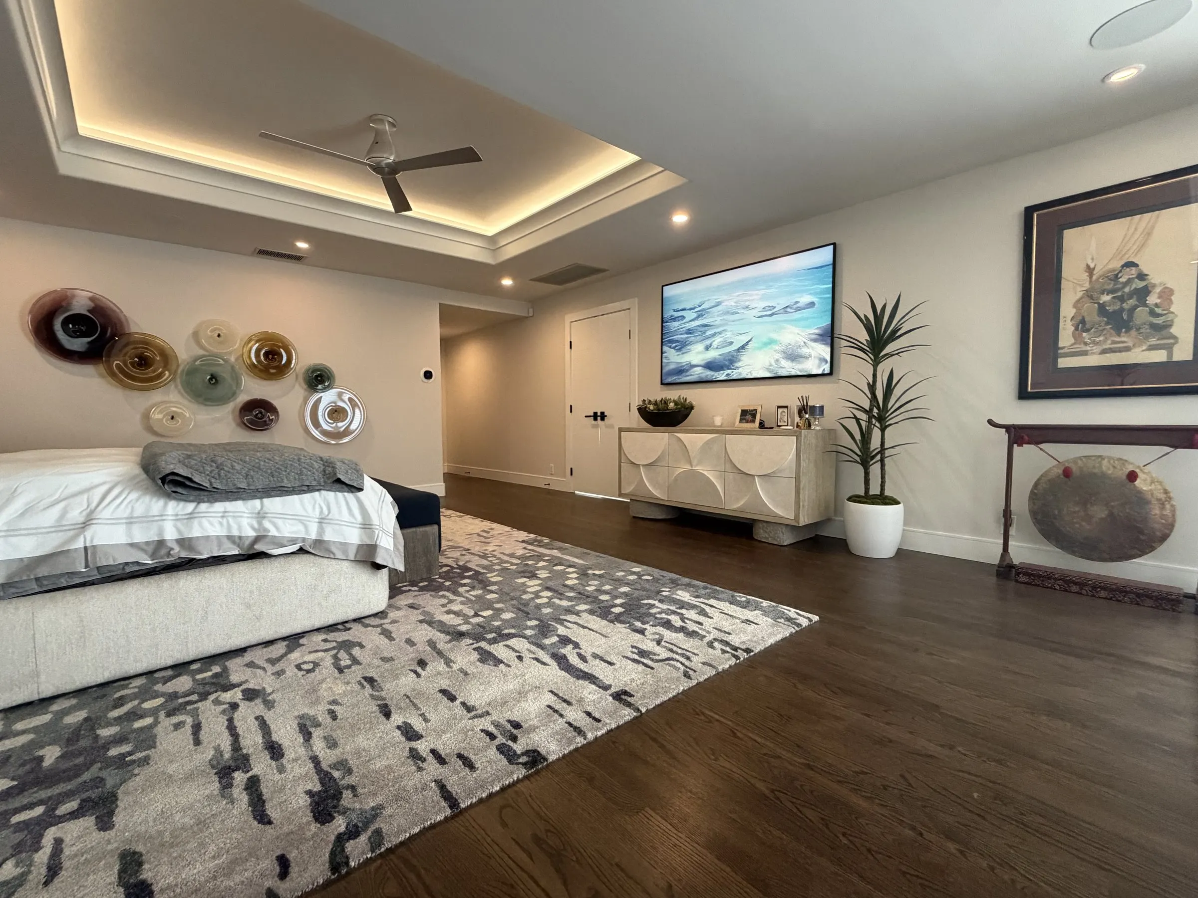 Primary bedroom with a wall-mounted display and a lit ceiling cove