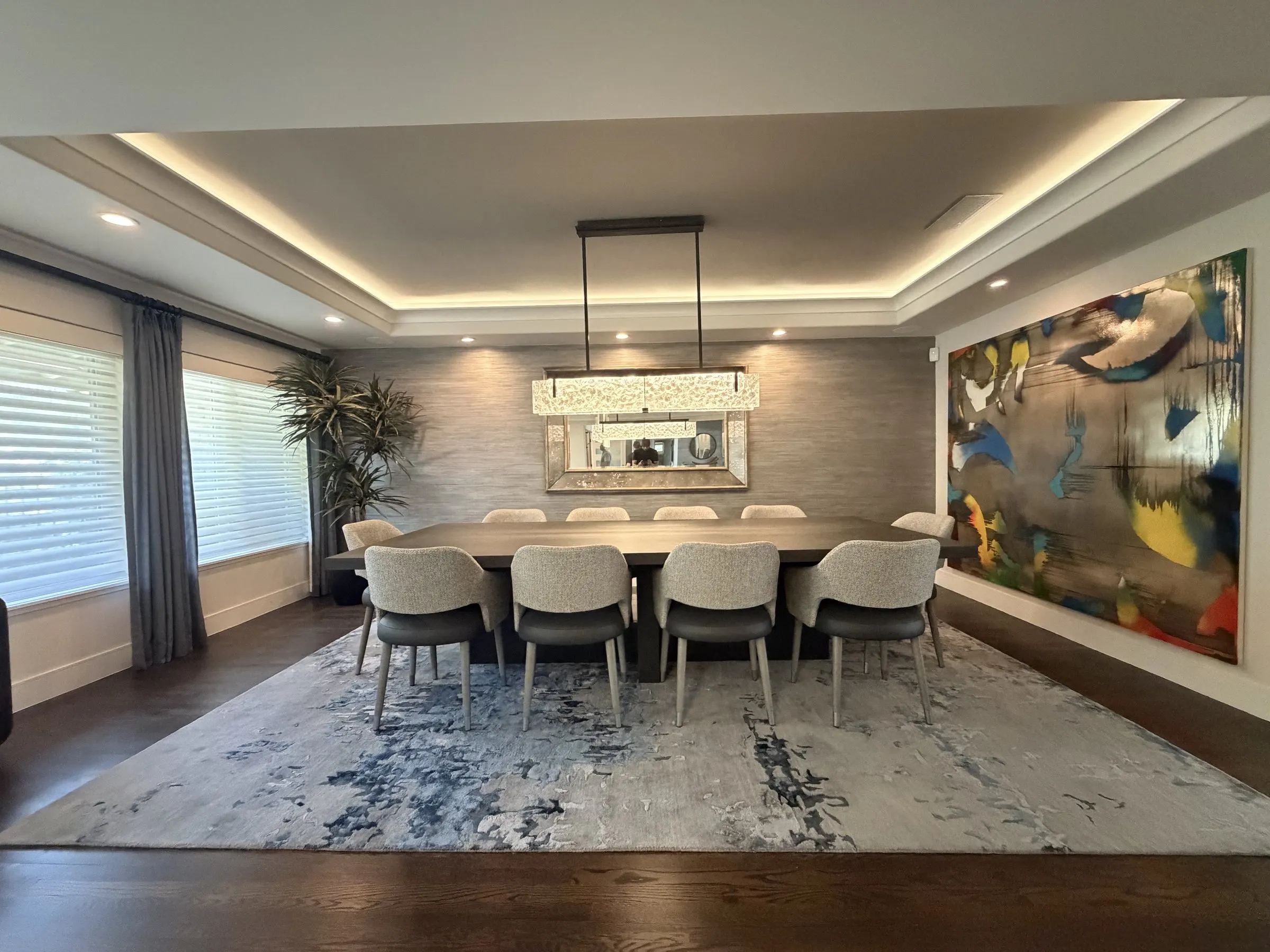 Dining room with a lit ceiling cove, rectangular pendant, and large abstract painting