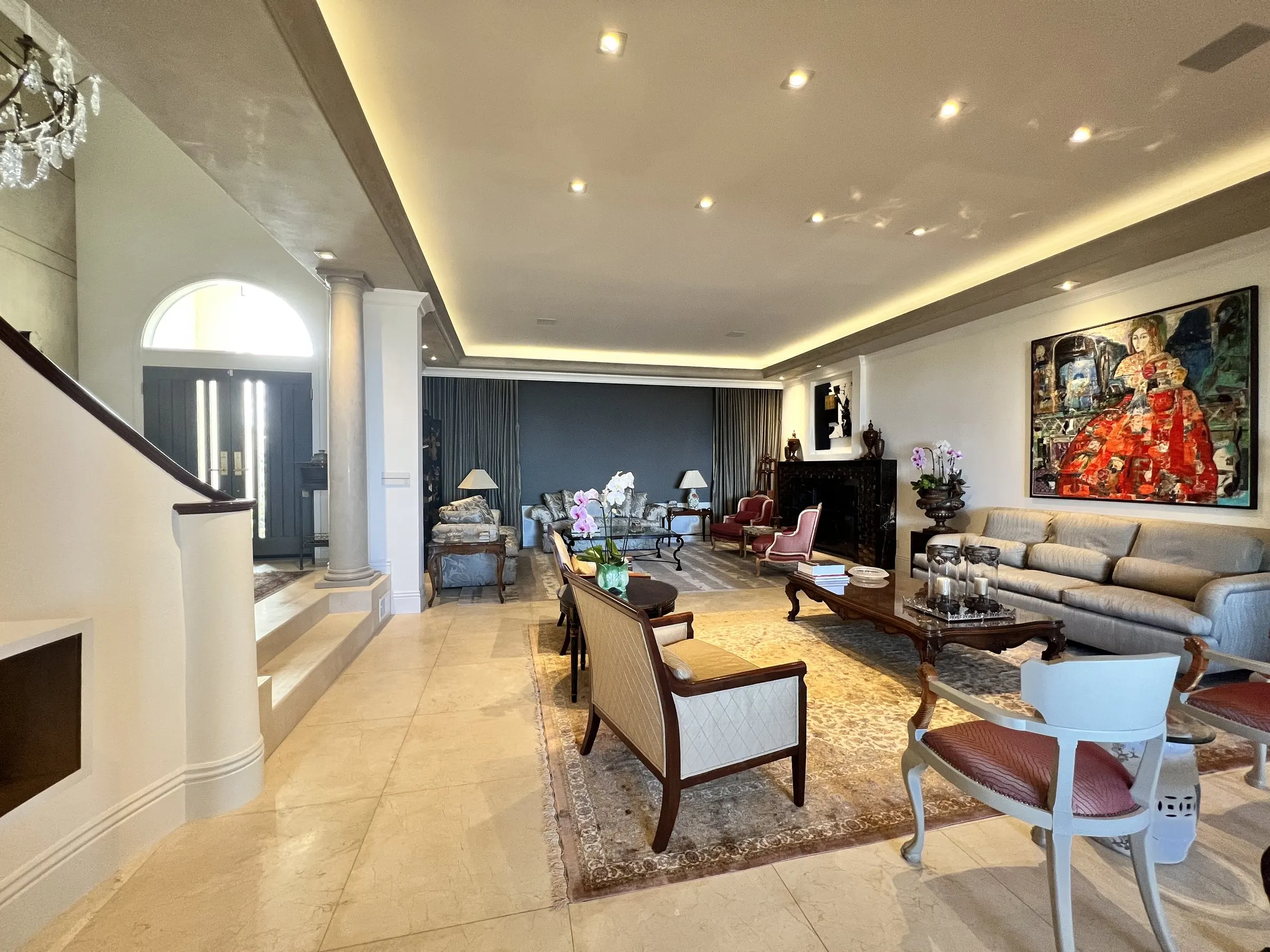 Long living room with warm cove lighting along the ceiling and recessed accent lights