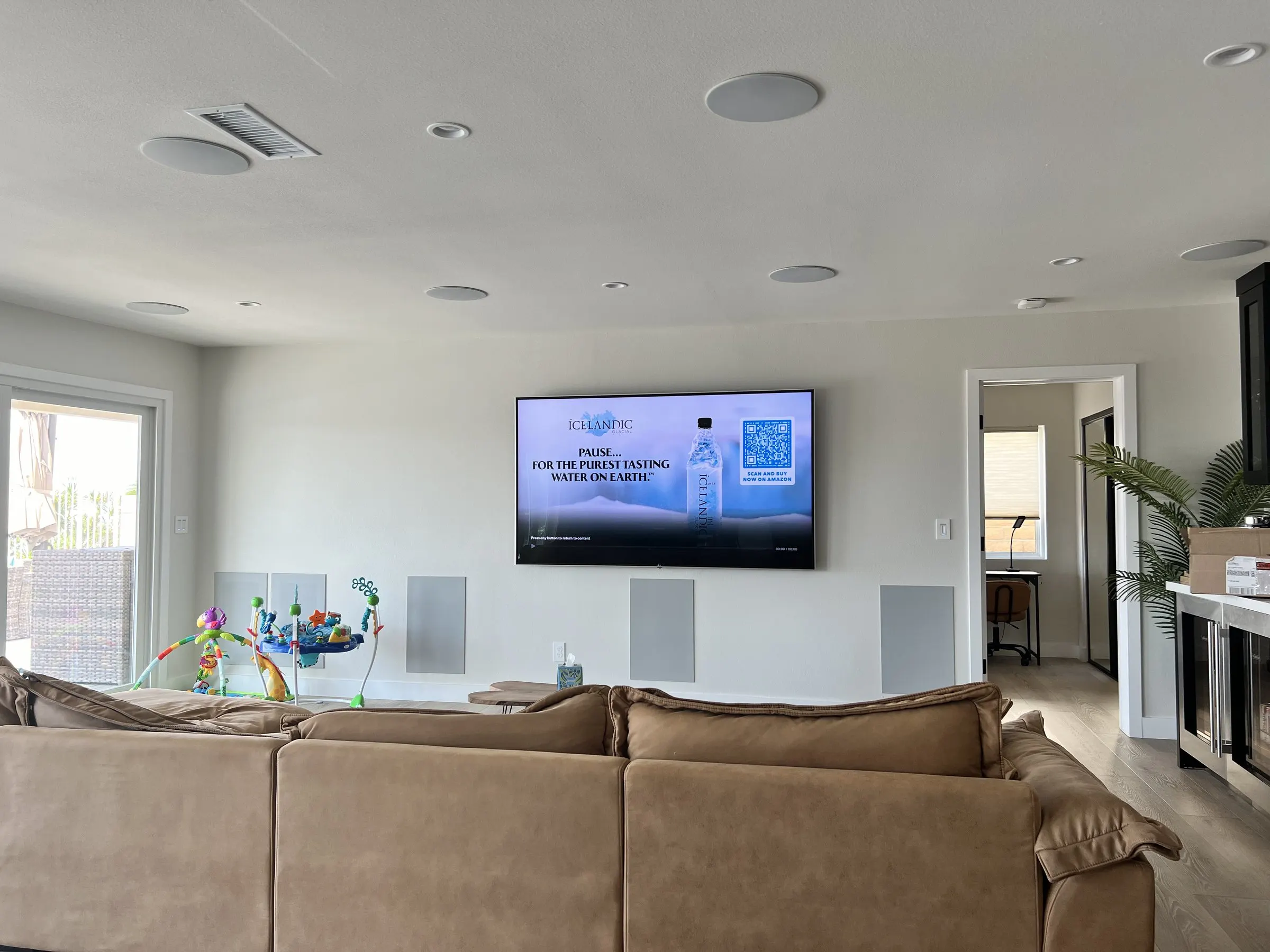 Family room with a sectional sofa, wall display, and in-wall speakers