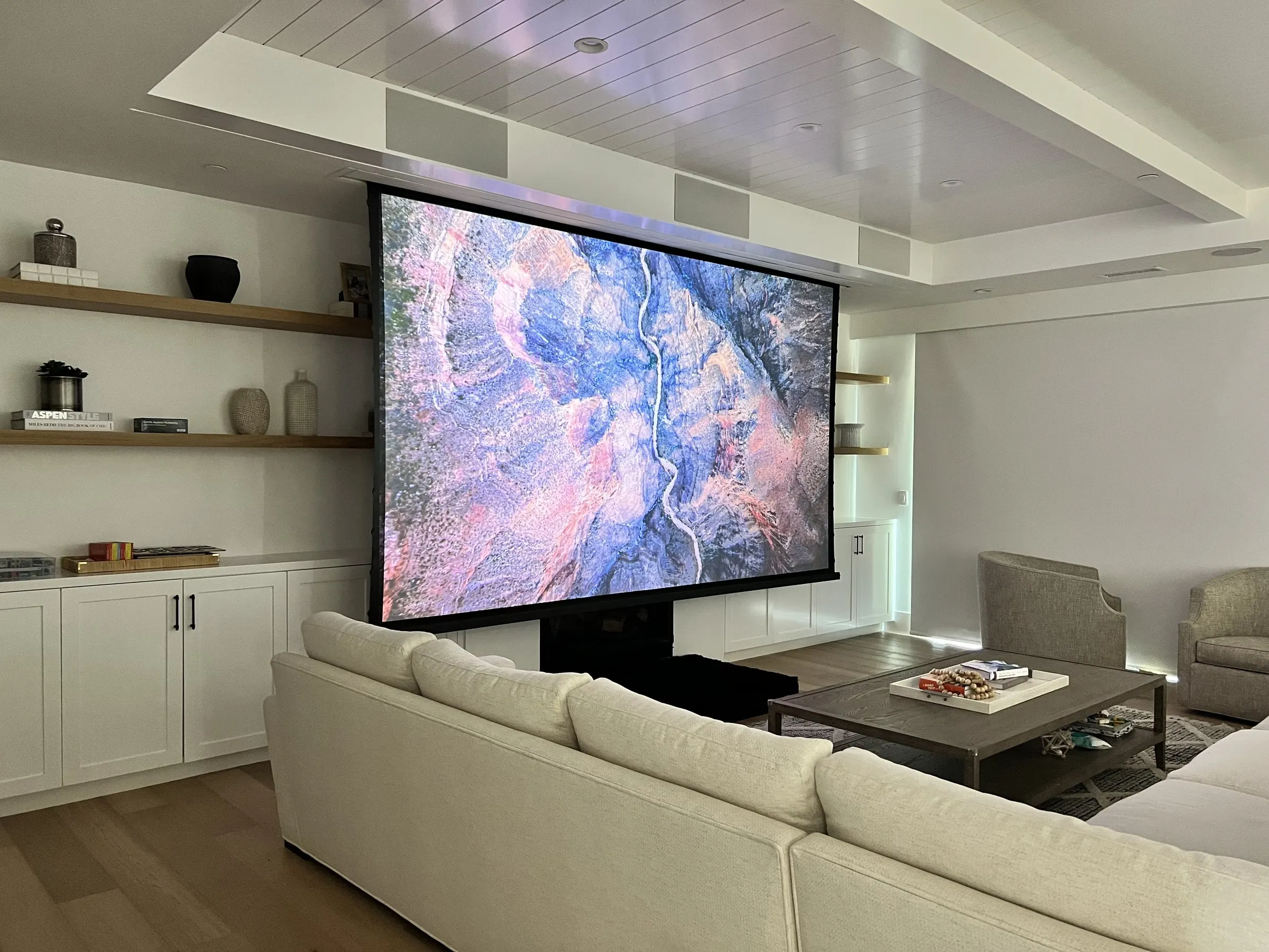 Close view of a large projection screen lowered in front of white built-in shelving