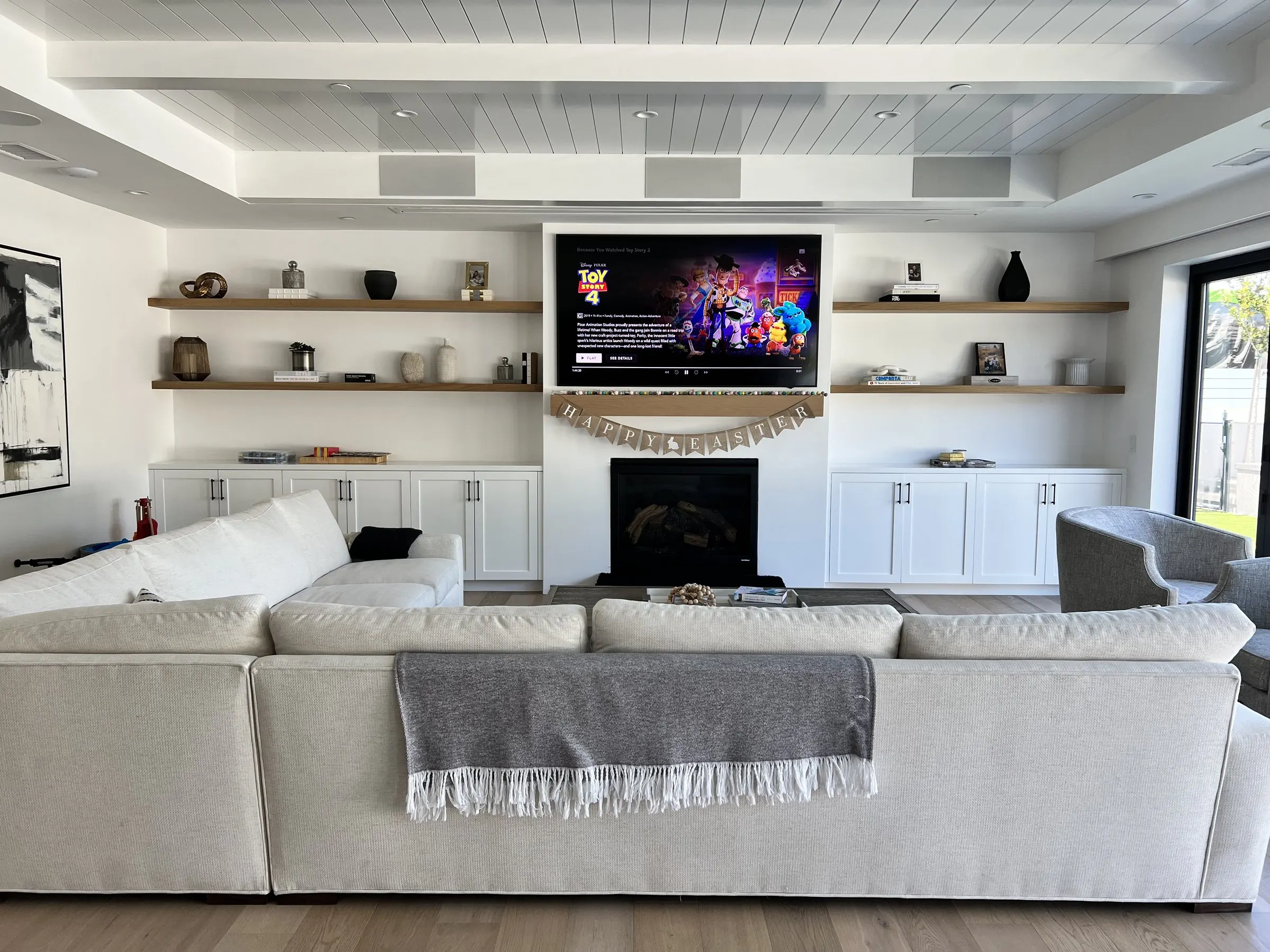 Family room with a television above the fireplace between open shelves