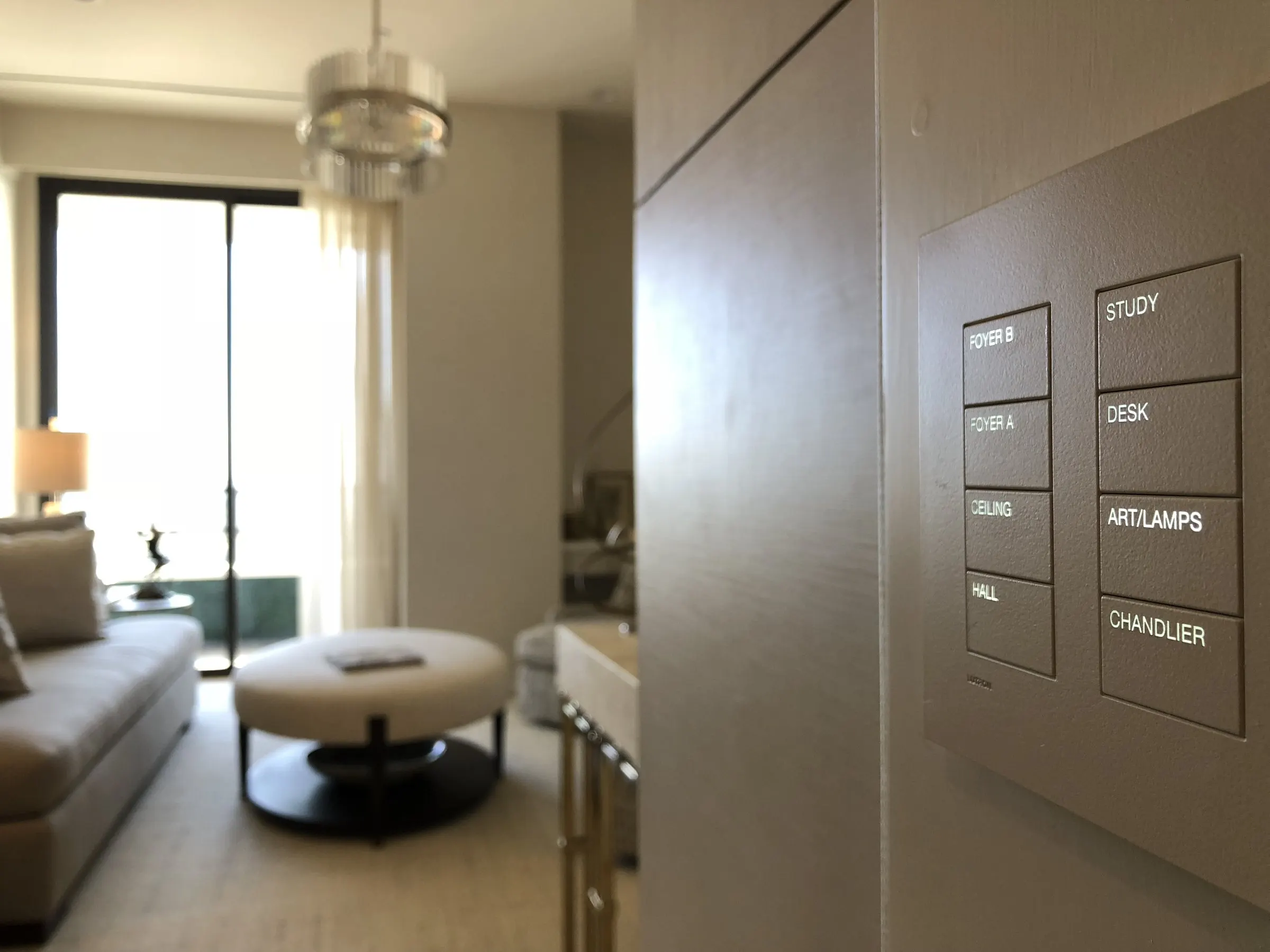 Close-up of an engraved lighting keypad with a softly lit living room in the background