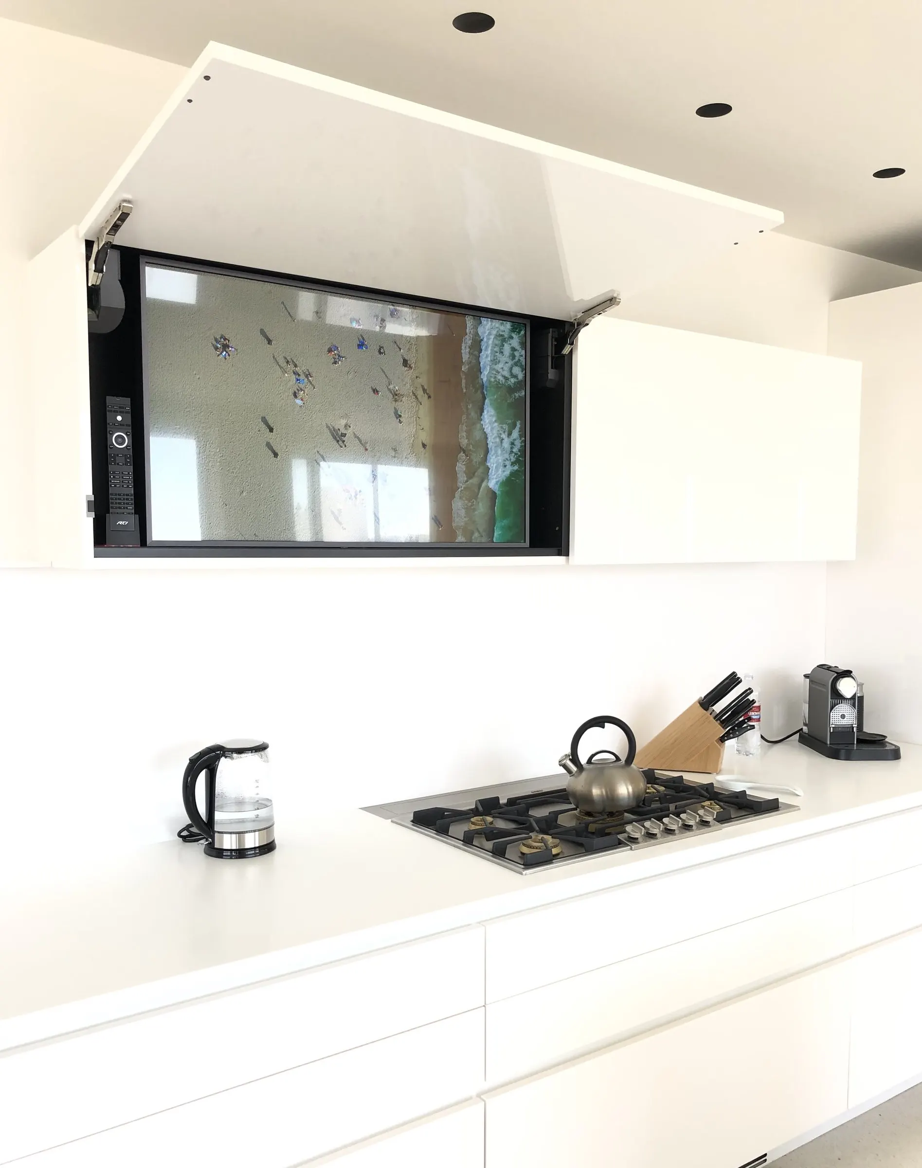 Kitchen cabinet lift raised to reveal a television above the counter