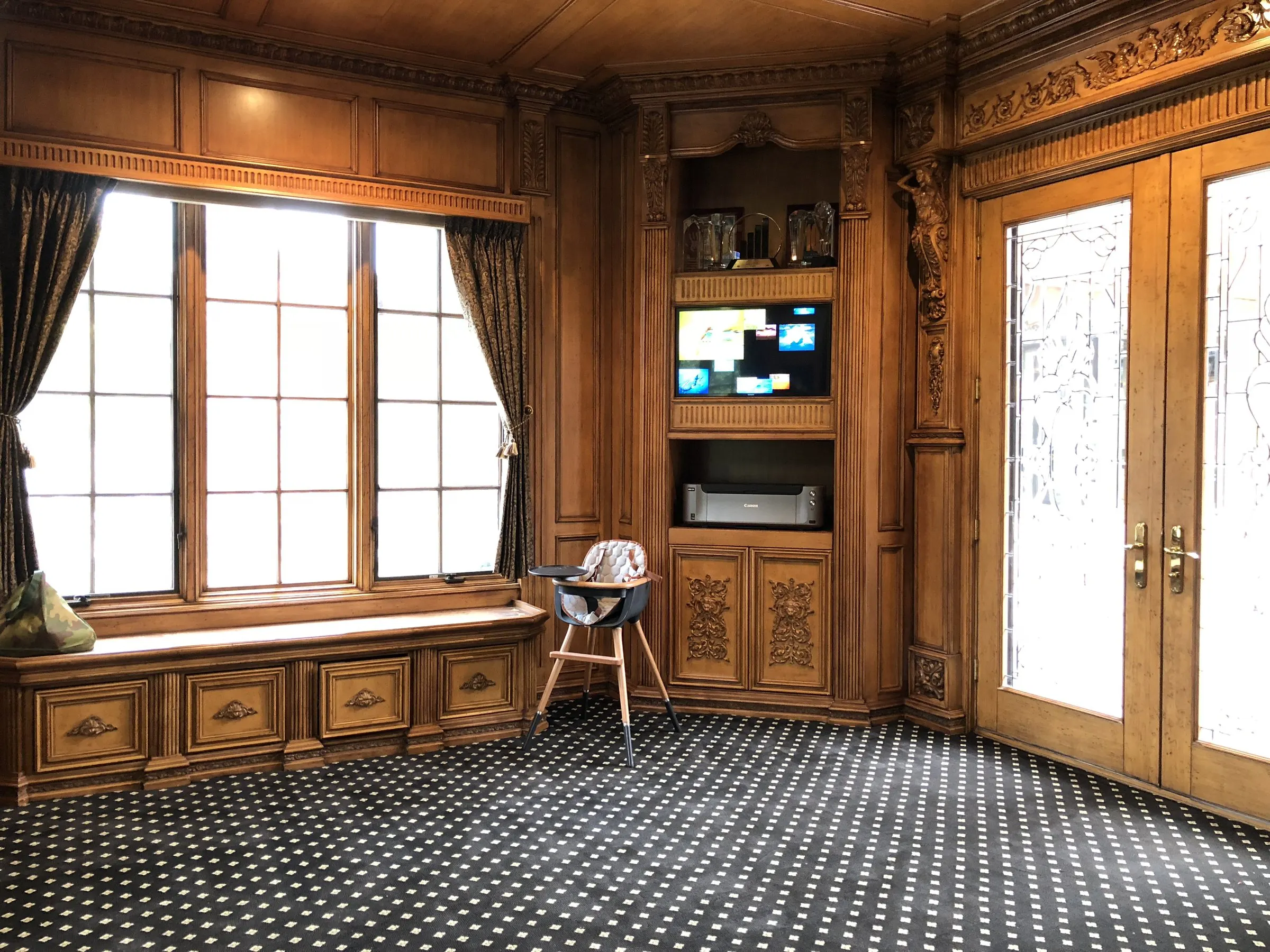 Wood-paneled library with a television set into carved built-in cabinetry