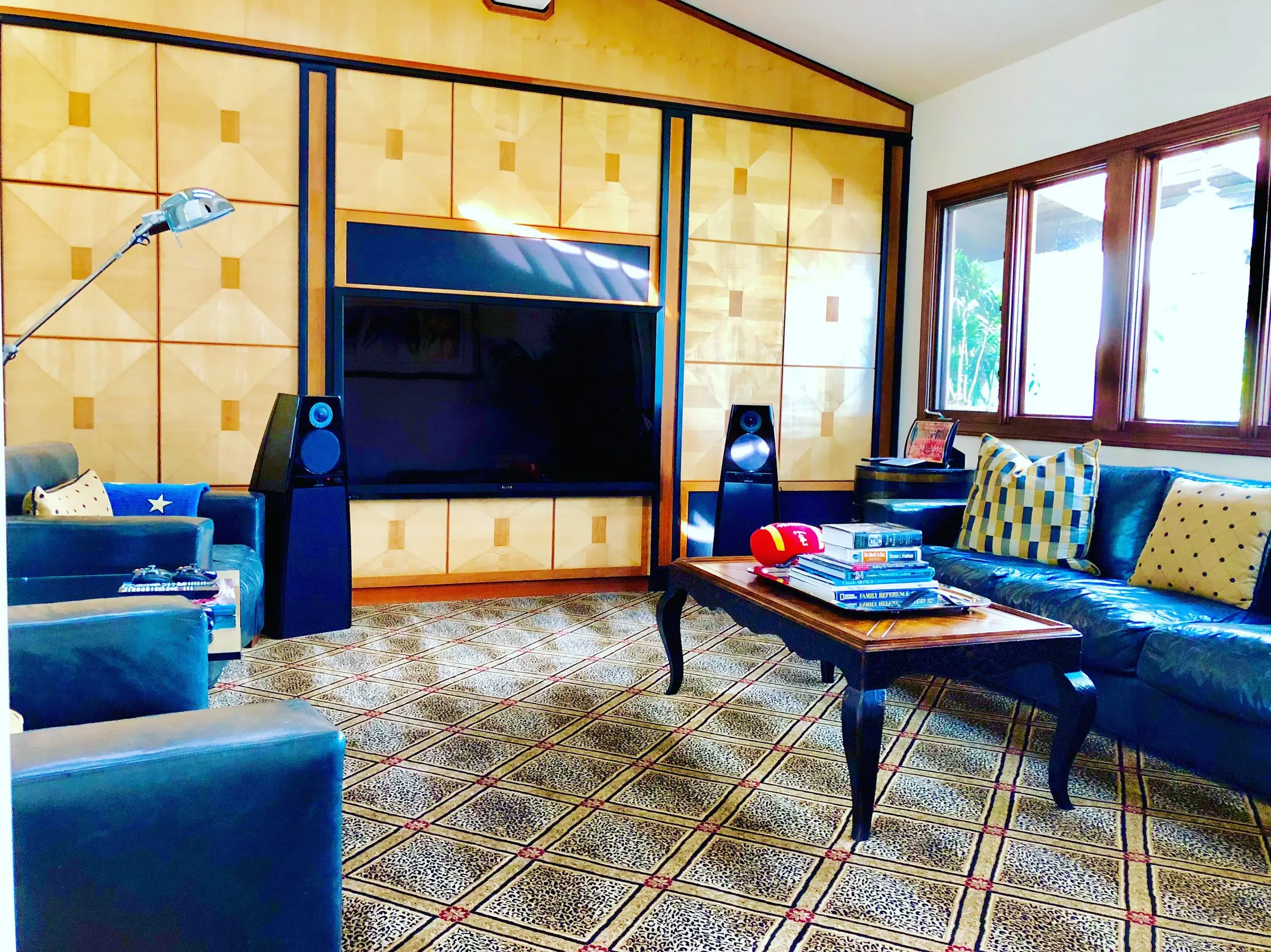 Living room with tall black tower speakers flanking a television set in wood-paneled millwork