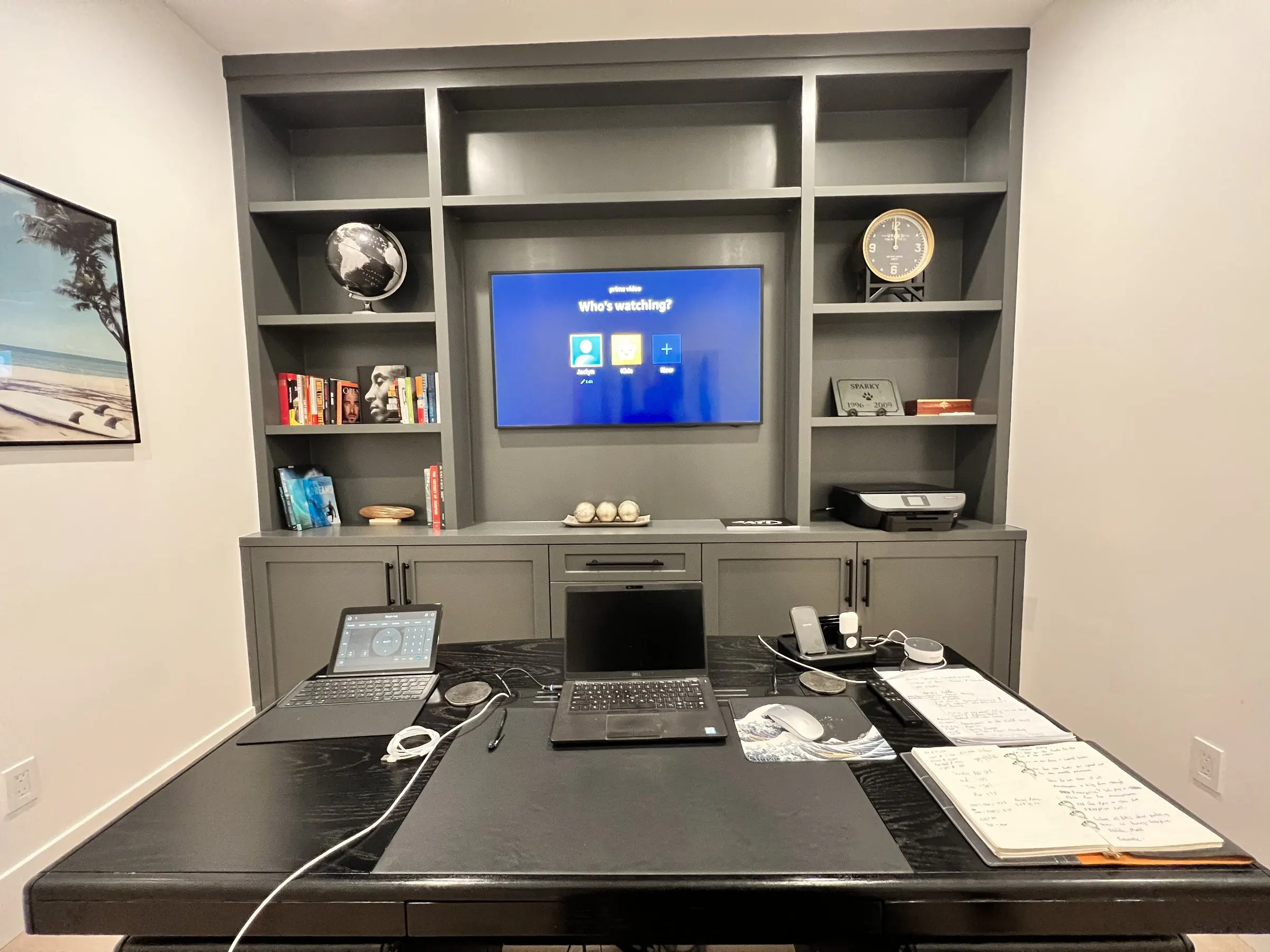 Home office with a television built into gray shelving above a desk
