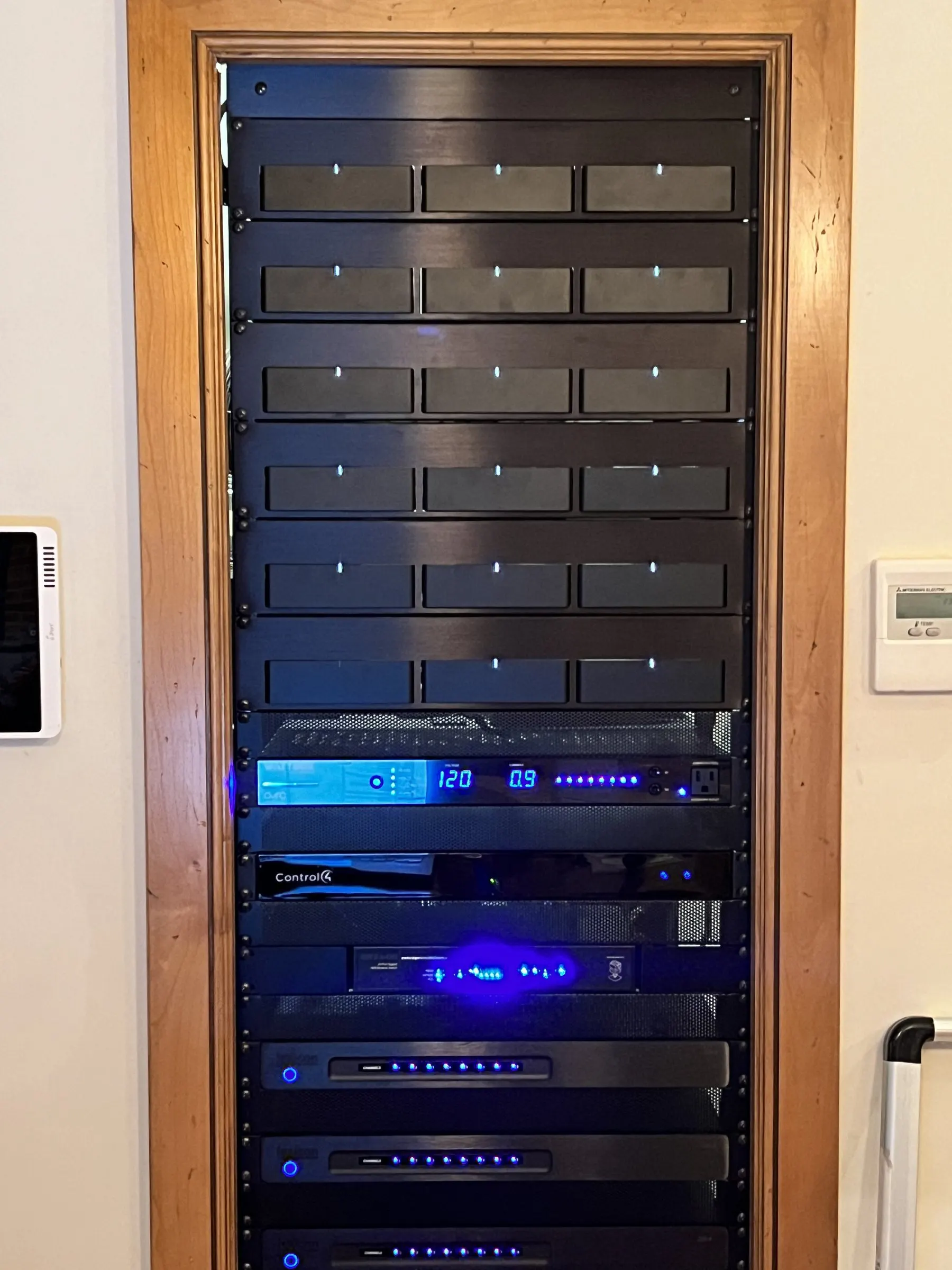 Equipment rack with vented panels and amplifiers inside a wood-trimmed closet