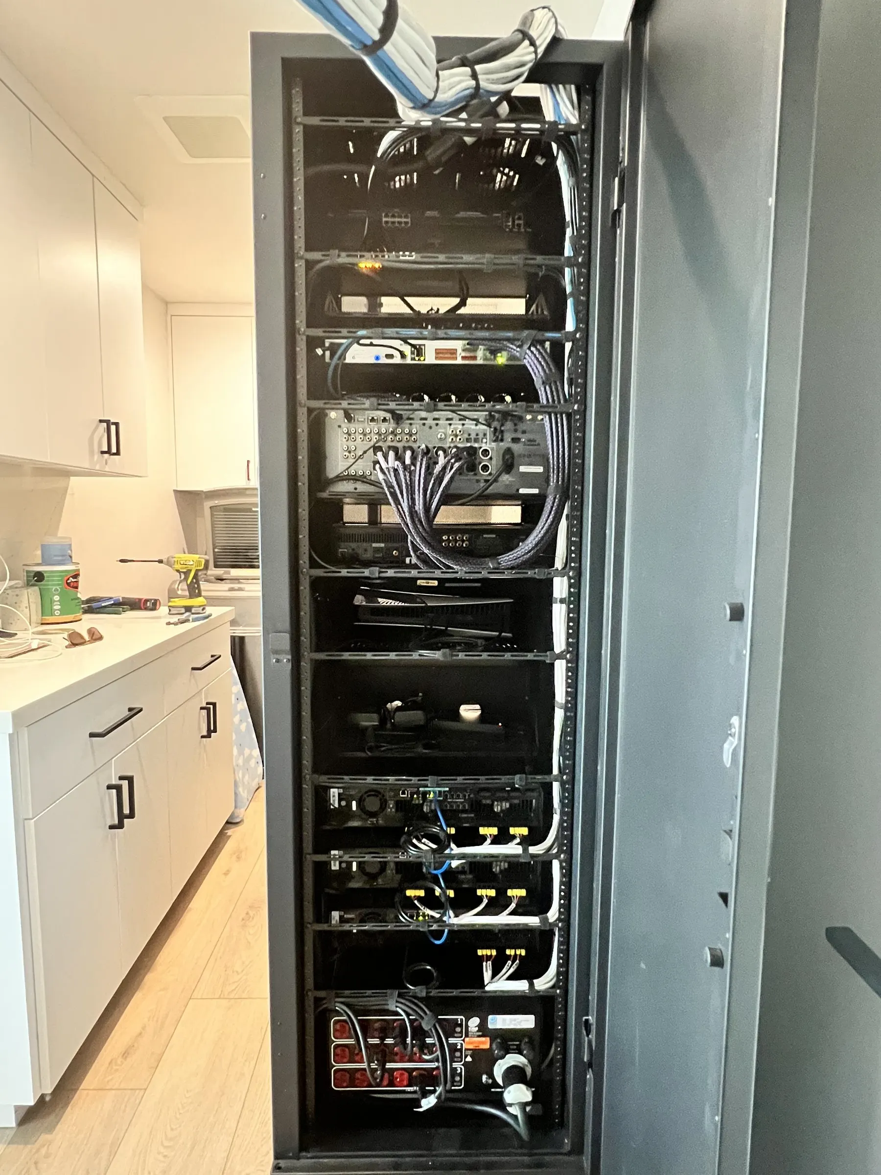 Equipment rack with cabling inside a closet beside a kitchen