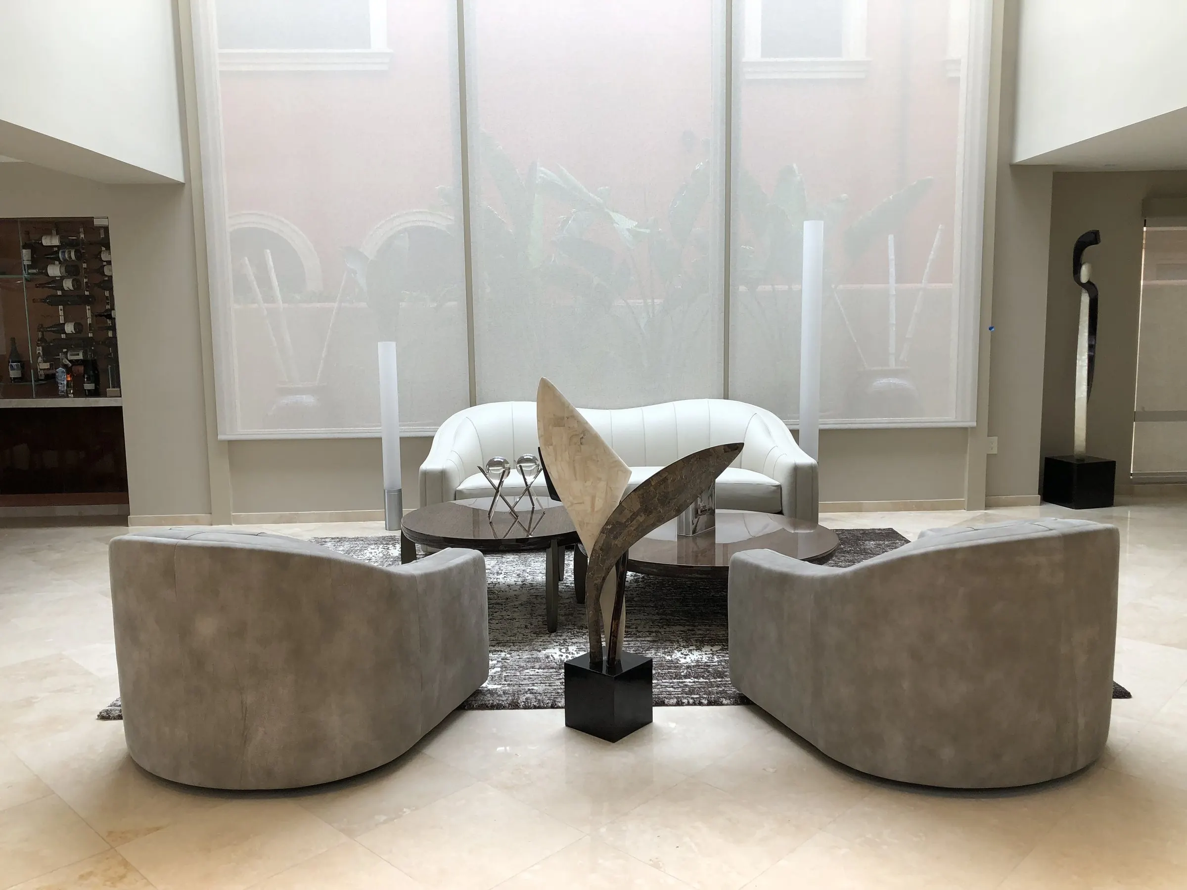 Sitting area beneath tall windows covered by sheer shades