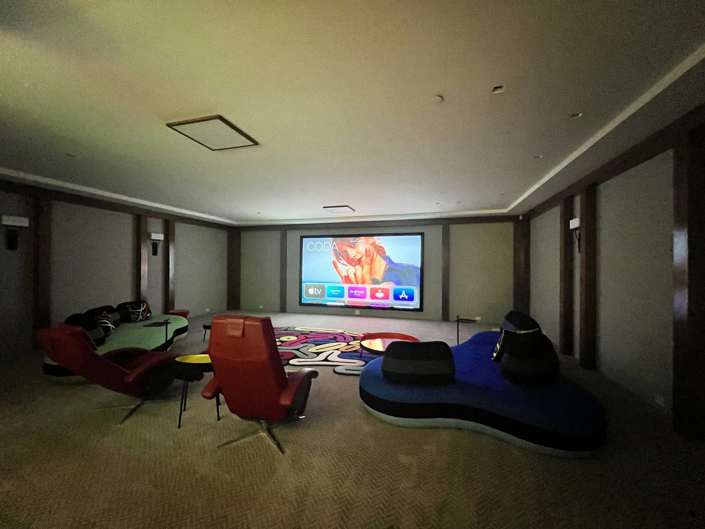 Lounge theater with dimmed wall sconces and a projected image on screen