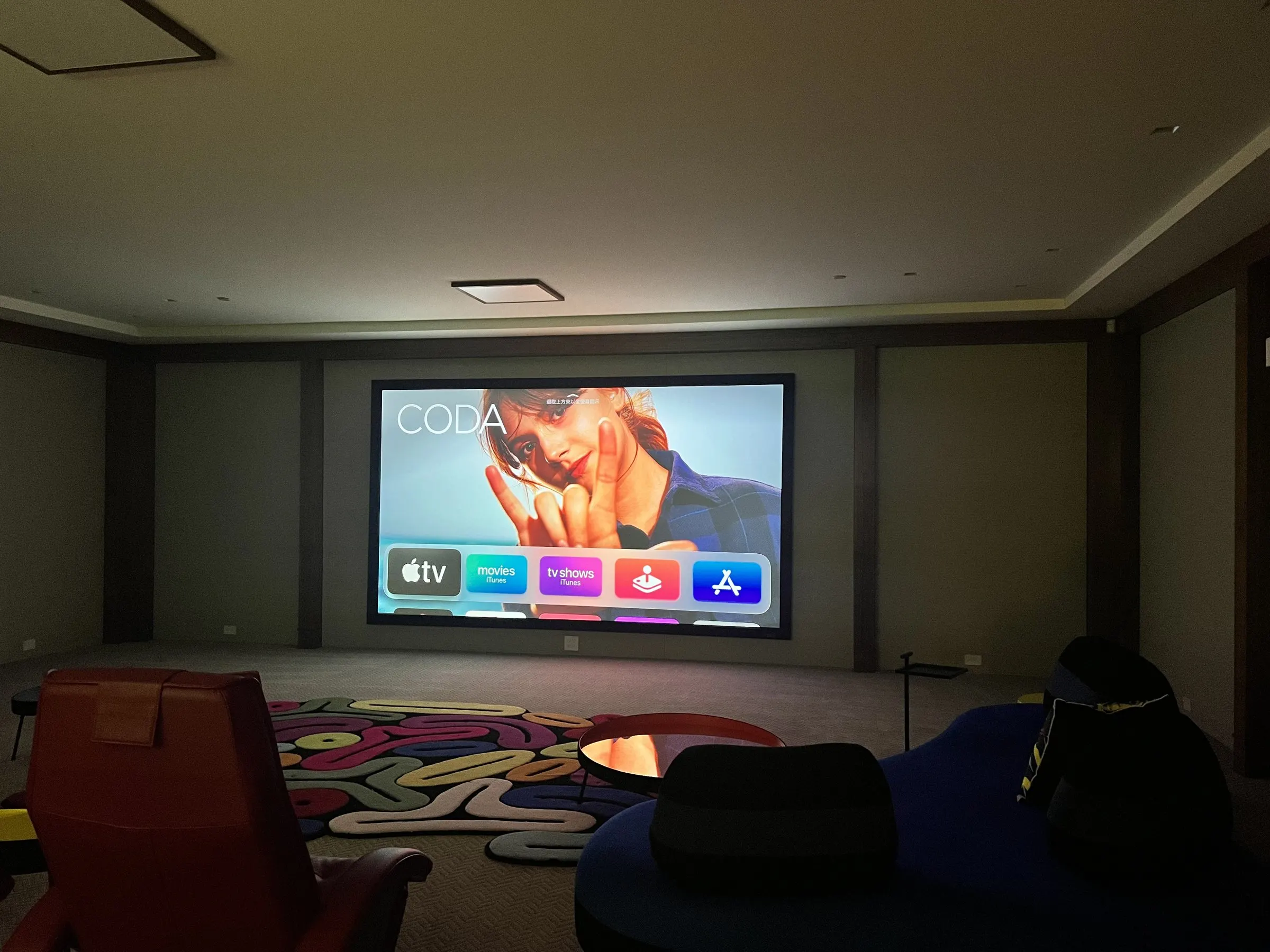 Dark lounge theater with a bright projected image and seating silhouetted in front