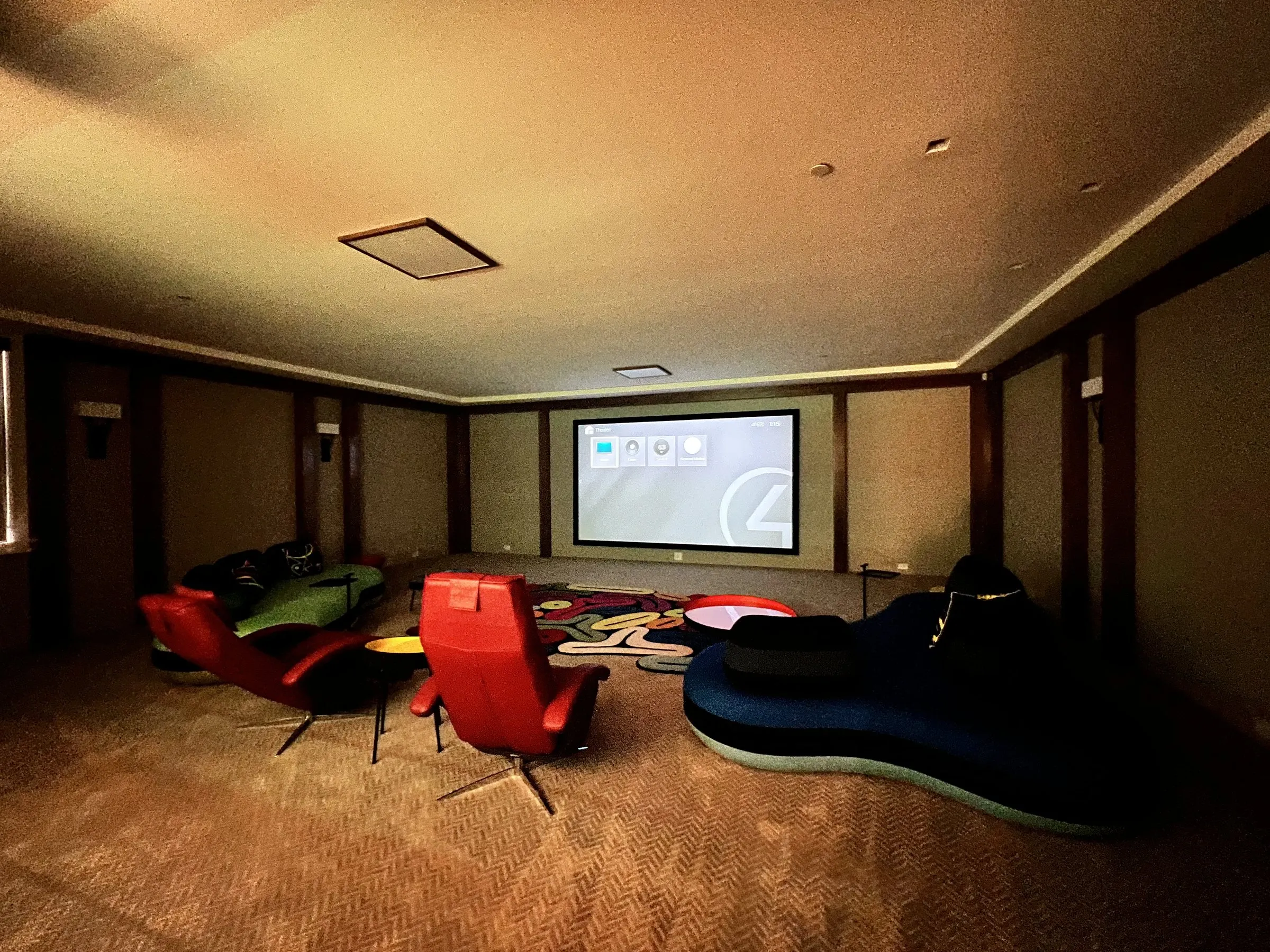 Lounge theater with warm dimmed sconces and a projected image on screen