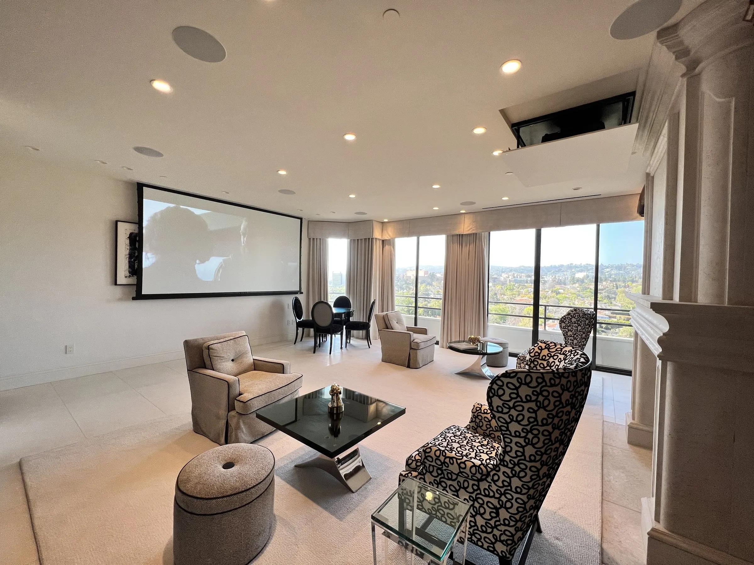 Living room with a ceiling projector lift open and a screen lowered on the far wall