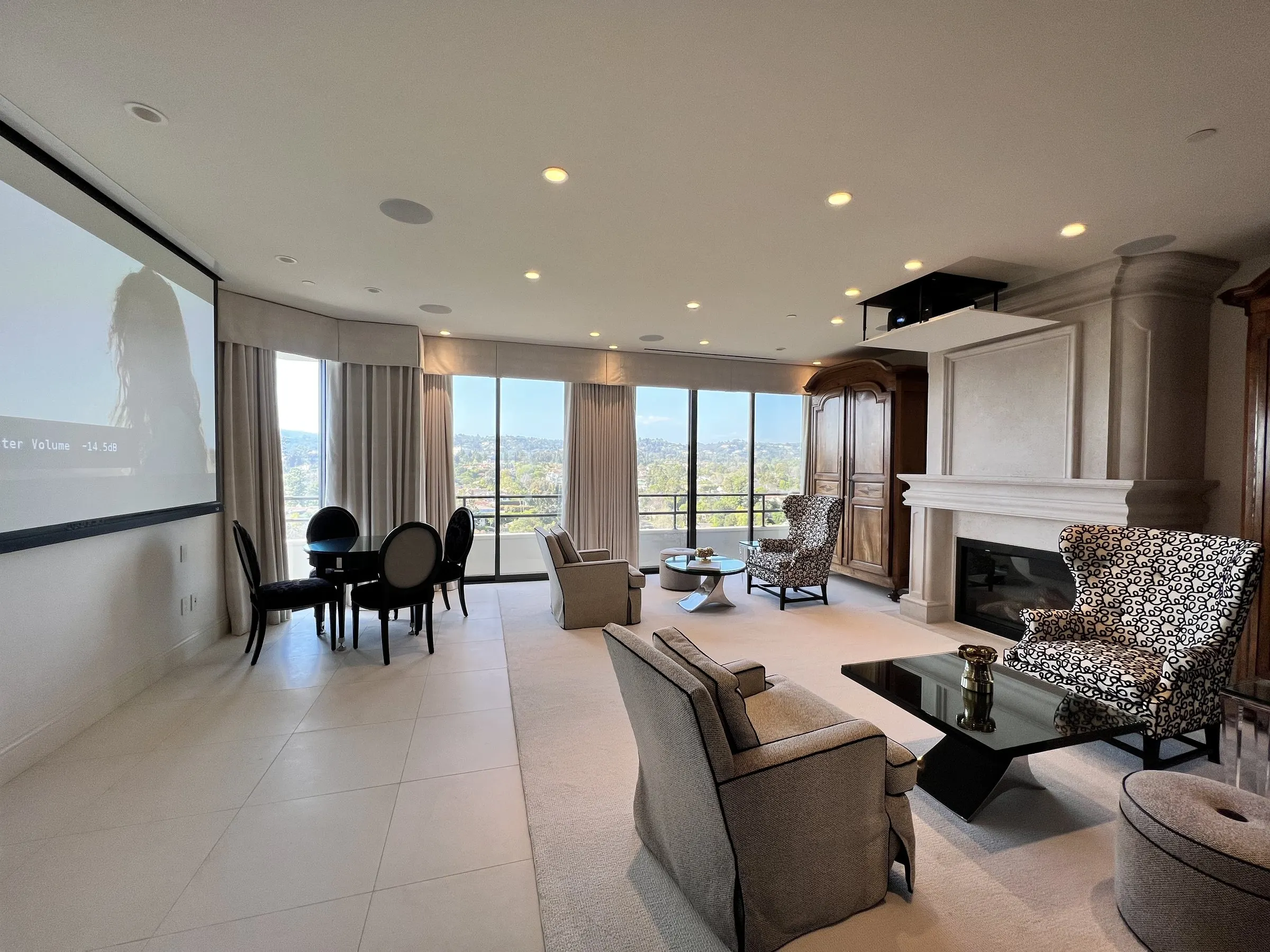 High-rise living room with a projection screen lowered on the side wall and city views beyond